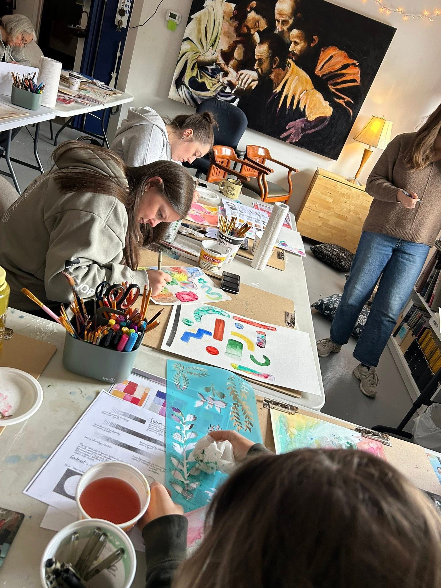 Group painting in art studio with colorful supplies and artwork.