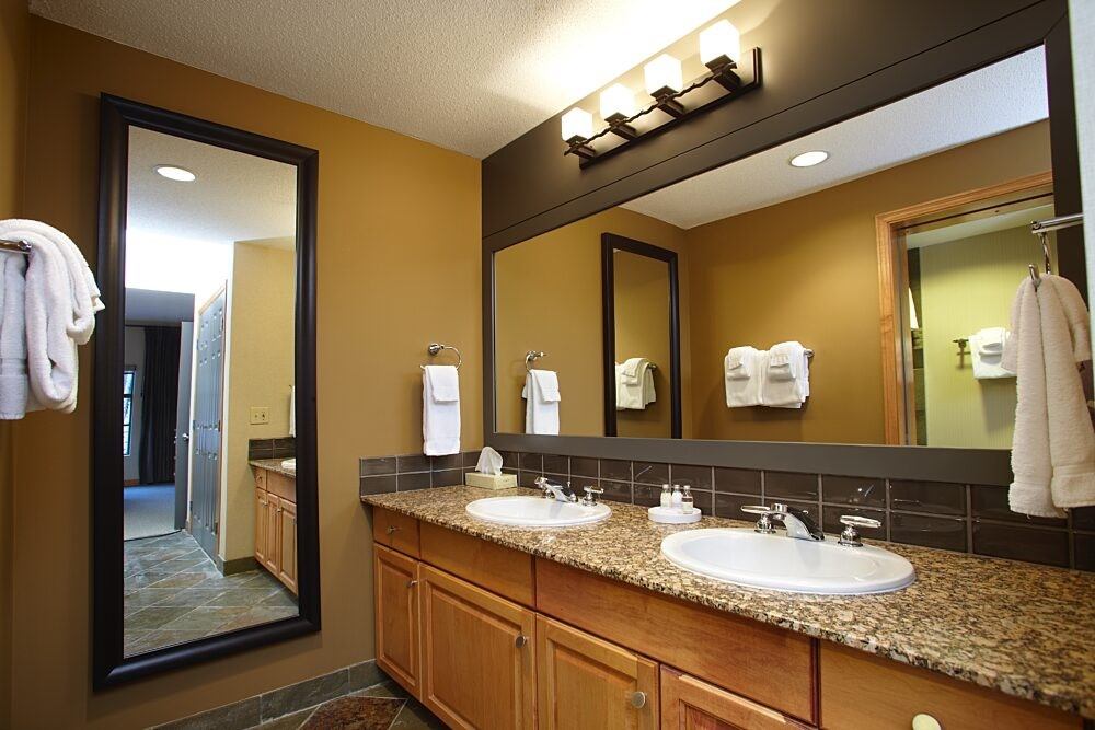 Bathroom featuring granite countertop, two sinks, and large mirror