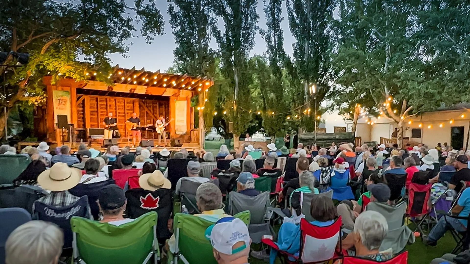Audience sitting in lawn chairs outside watching the festival.