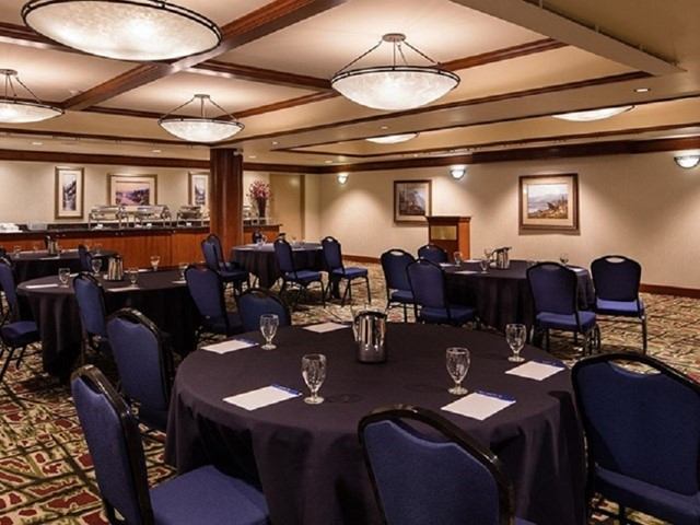 Banquet room with round tables, blue chairs, buffet counter and podium.