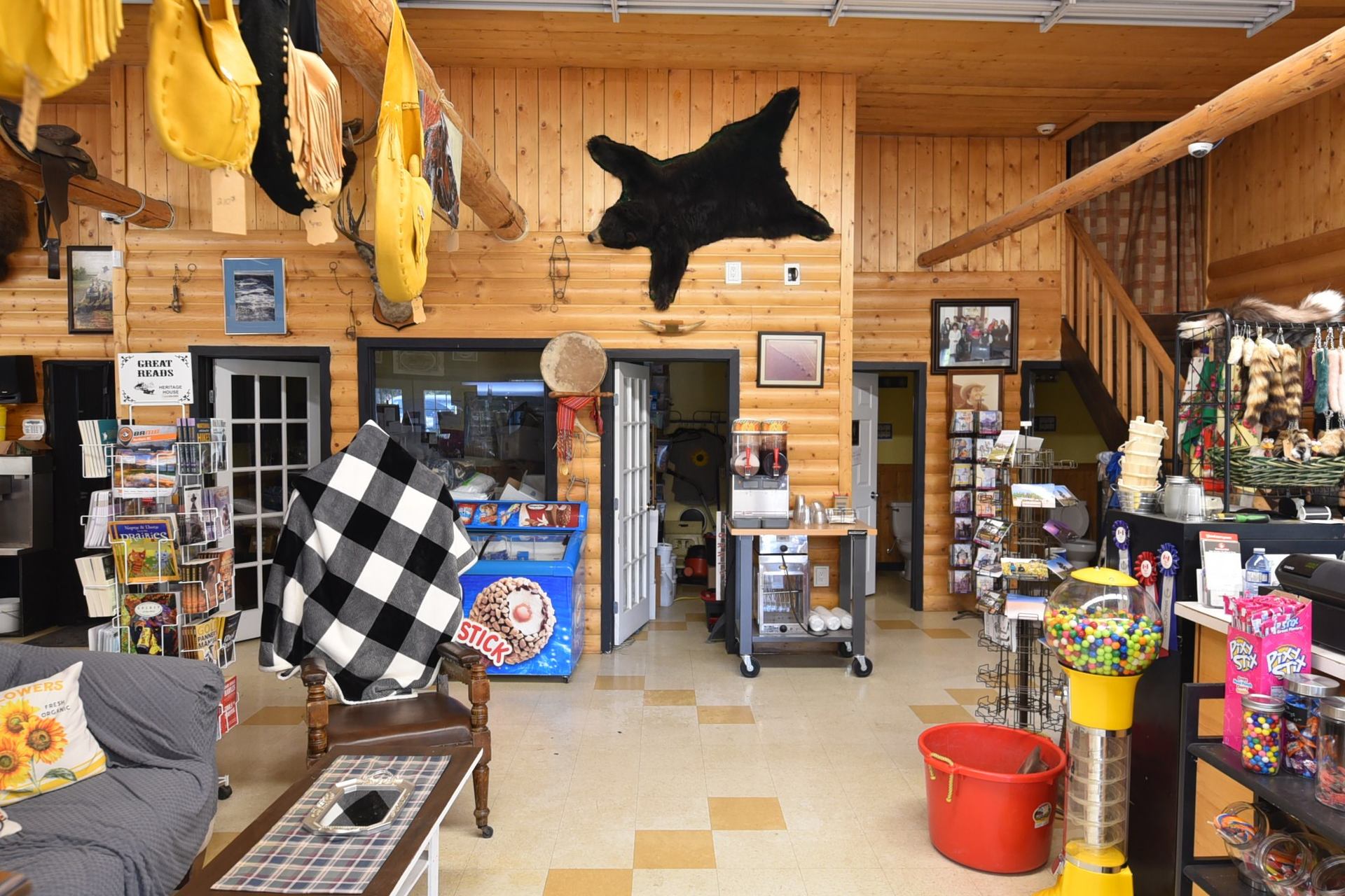 Log-walled lobby with souvenir racks, snack freezer, gumball machine and mounted bear rug.
