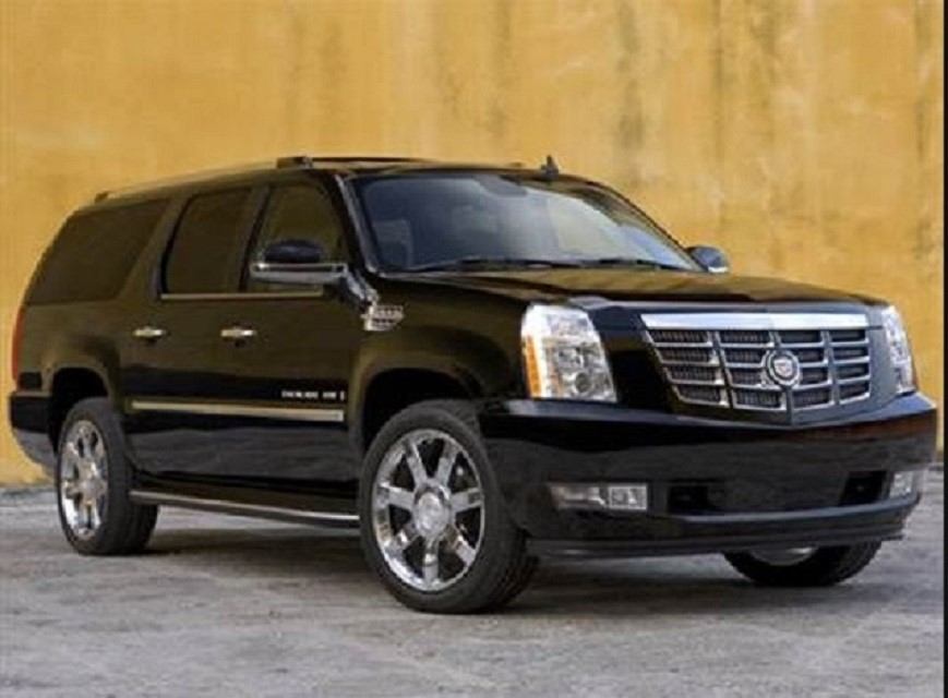 Black Cadillac Escalade SUV parked near a yellow wall by Airport Shuttle Express Ltd.