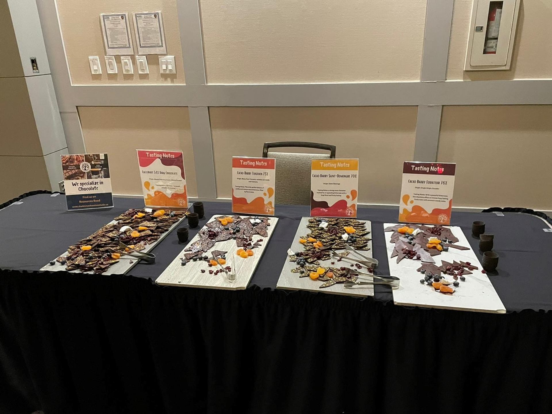 Table with labeled trays of assorted chocolate samples for tasting.