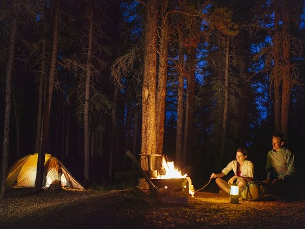 A young couple sitting by the campfire while camping in Cypress Hills Interprovincial Park.