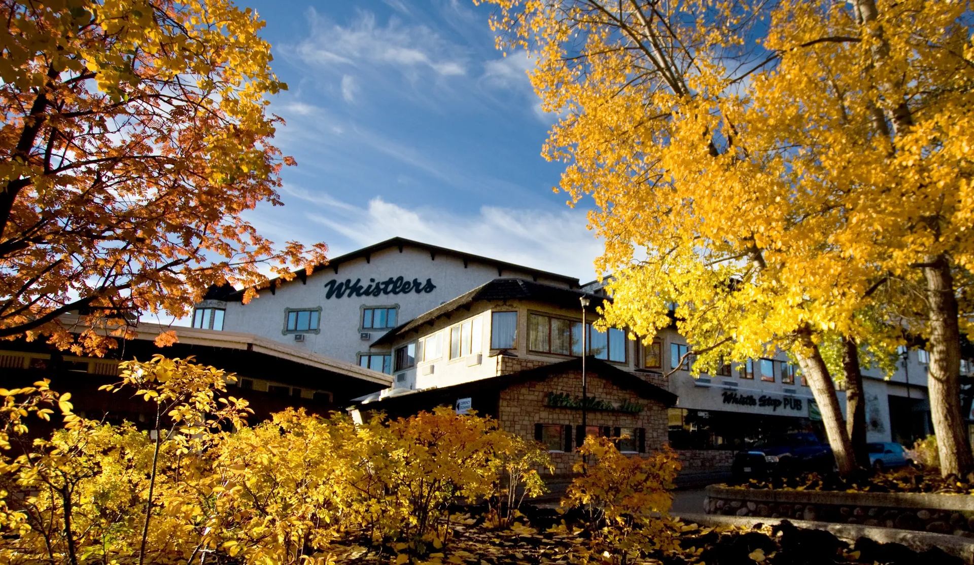 Whistlers building framed by bright autumn trees under a clear sky.