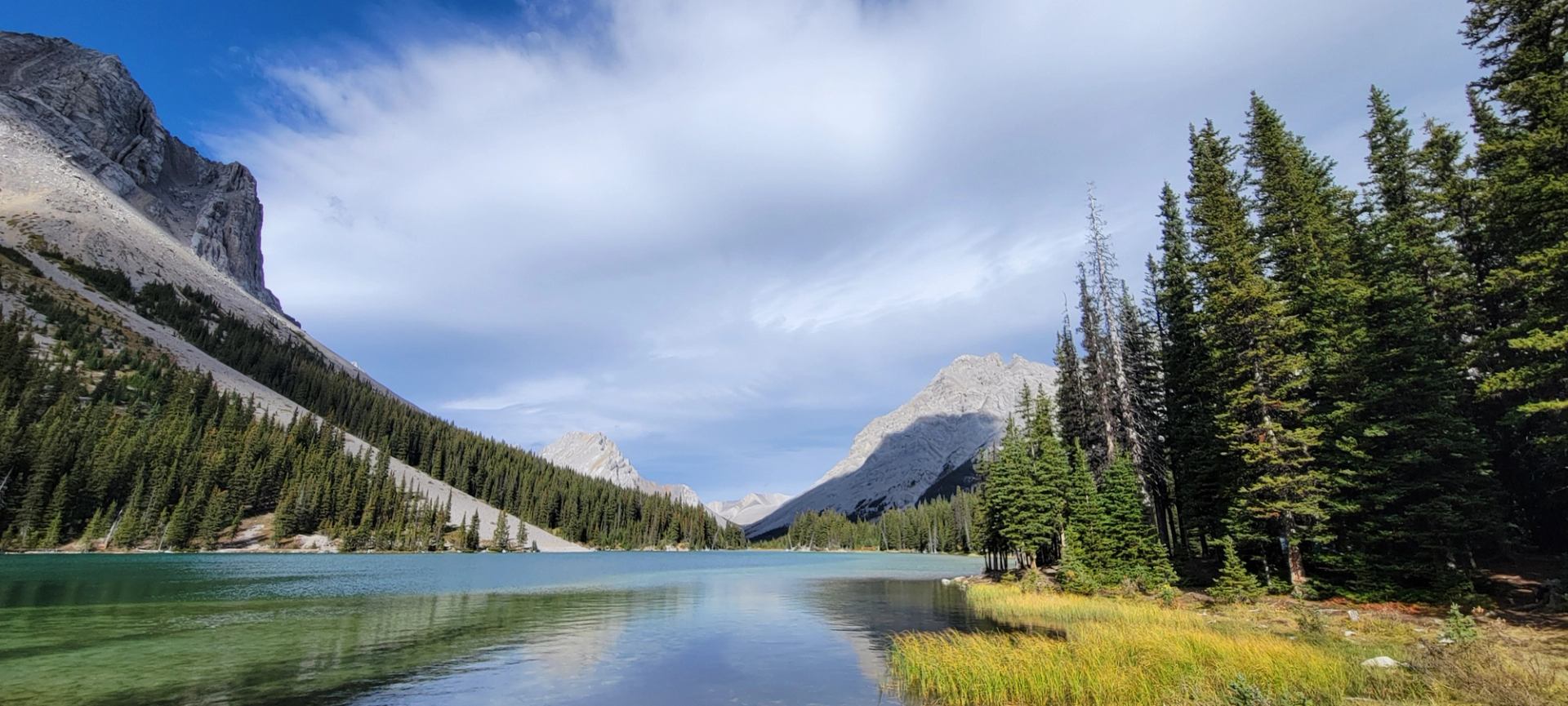 Turquoise mountain lake bordered by evergreen forest and steep rocky peaks.