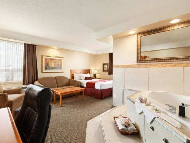 Comfortable suite featuring a bed, sofa, desk, and in-room jacuzzi tub