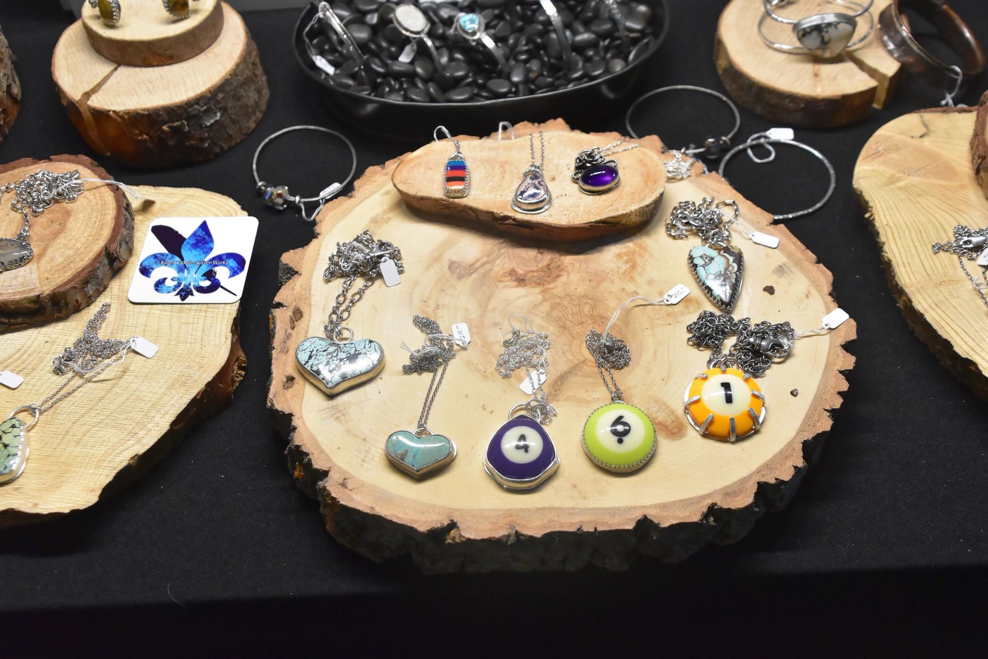 Display of handcrafted metal necklaces and pendants on wooden stands.