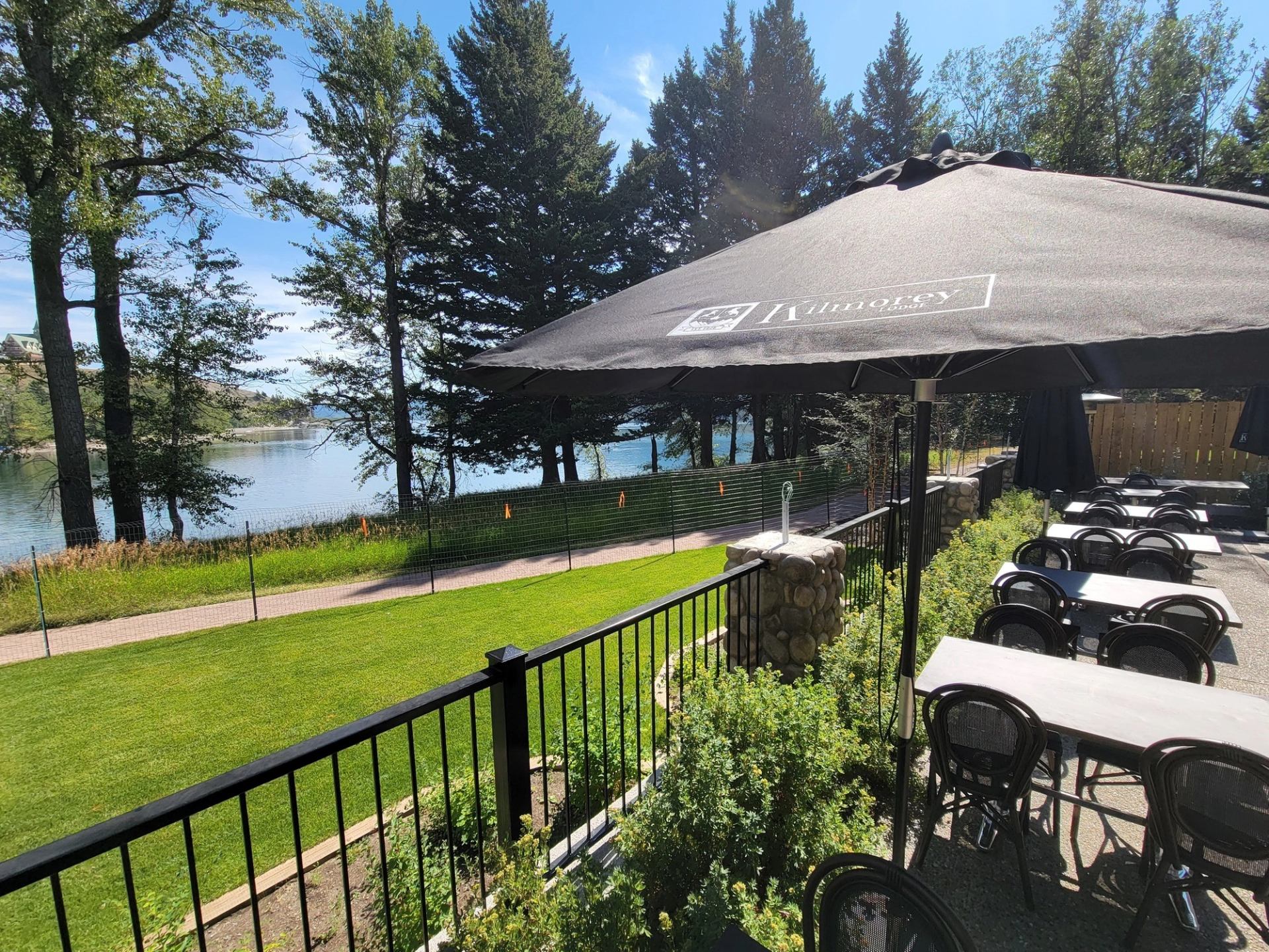 Outdoor seating with umbrella near water and trees at Kilmorey Lodge.