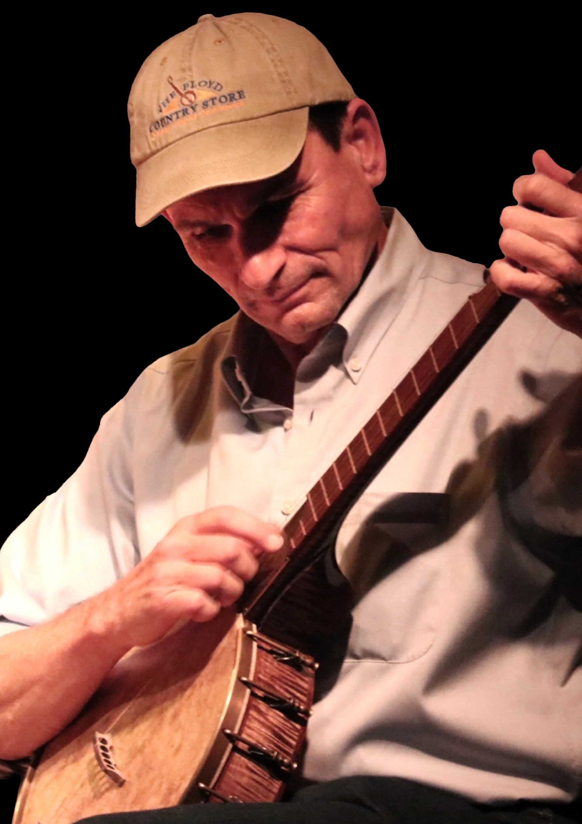 Musician in beige cap and buttoned shirt playing a wooden banjo against black background.