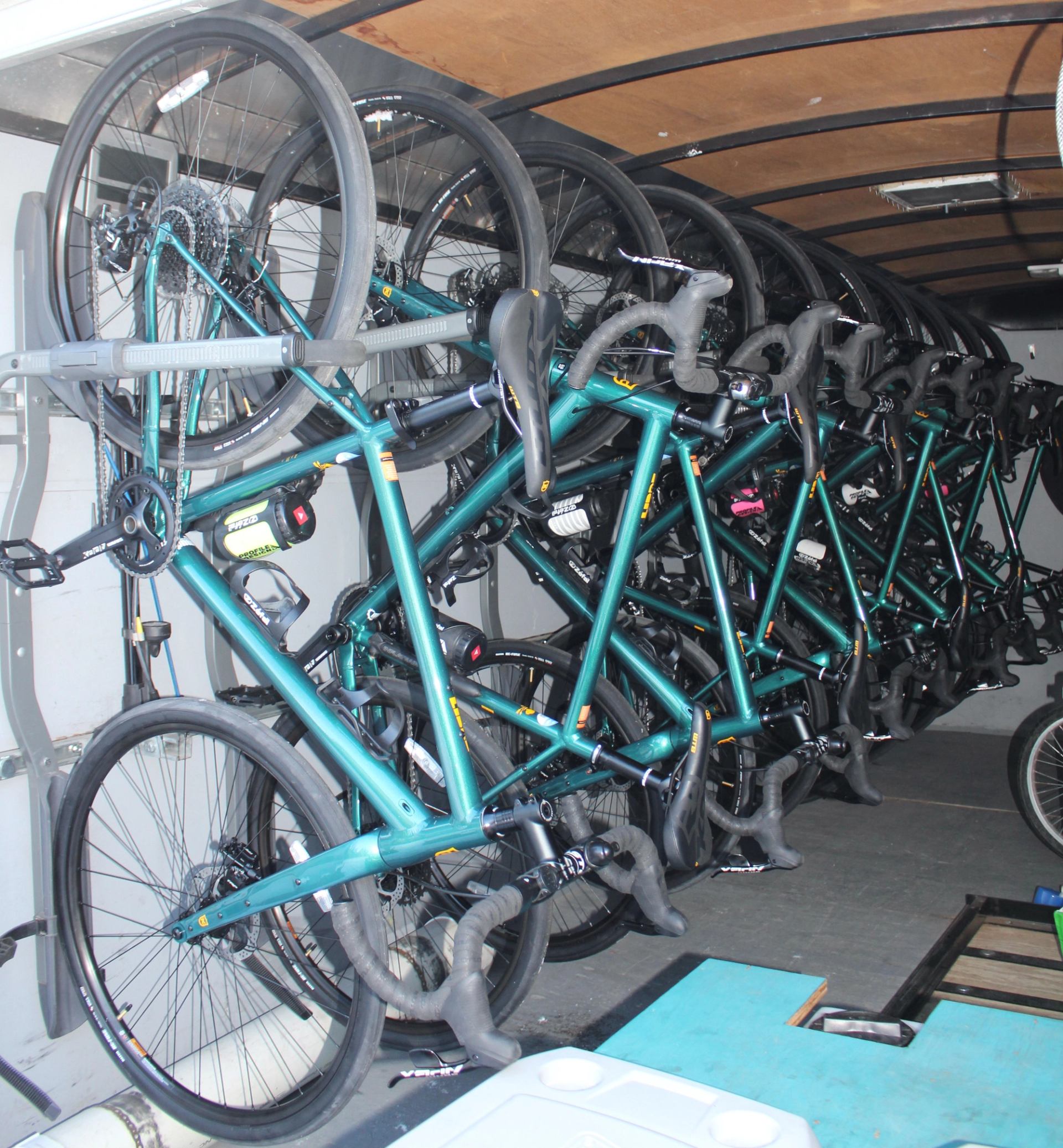 Teal bikes stacked vertically inside a trailer for transport.