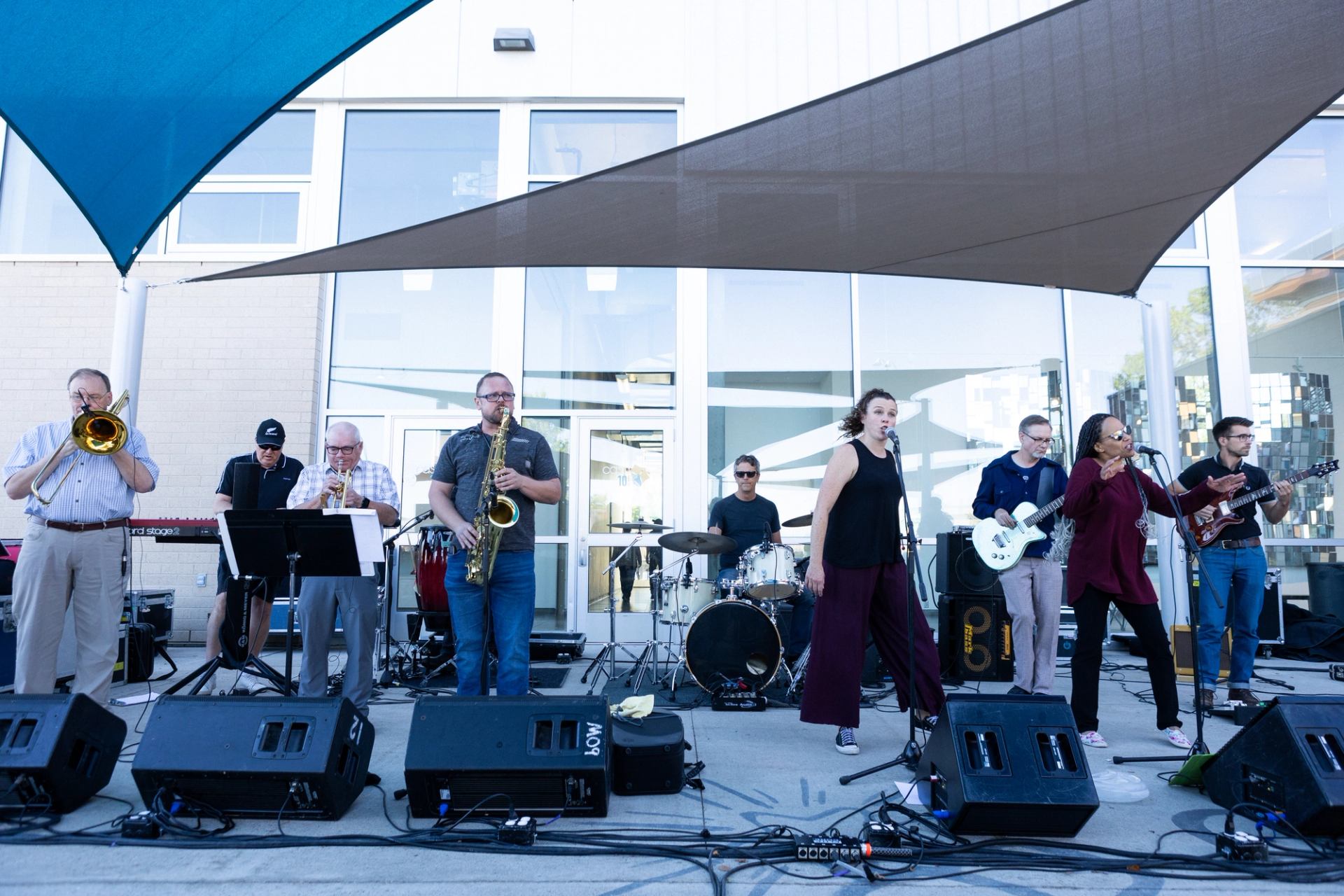 A nine piece band performs outside under shade sails in Rotary Square.