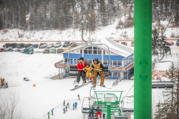 A family of three rides the chairlift before skiing Hidden Valley Ski Resort.