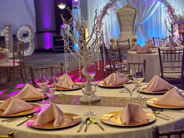 A dining table is set in a large room with birthday decorations in the background.