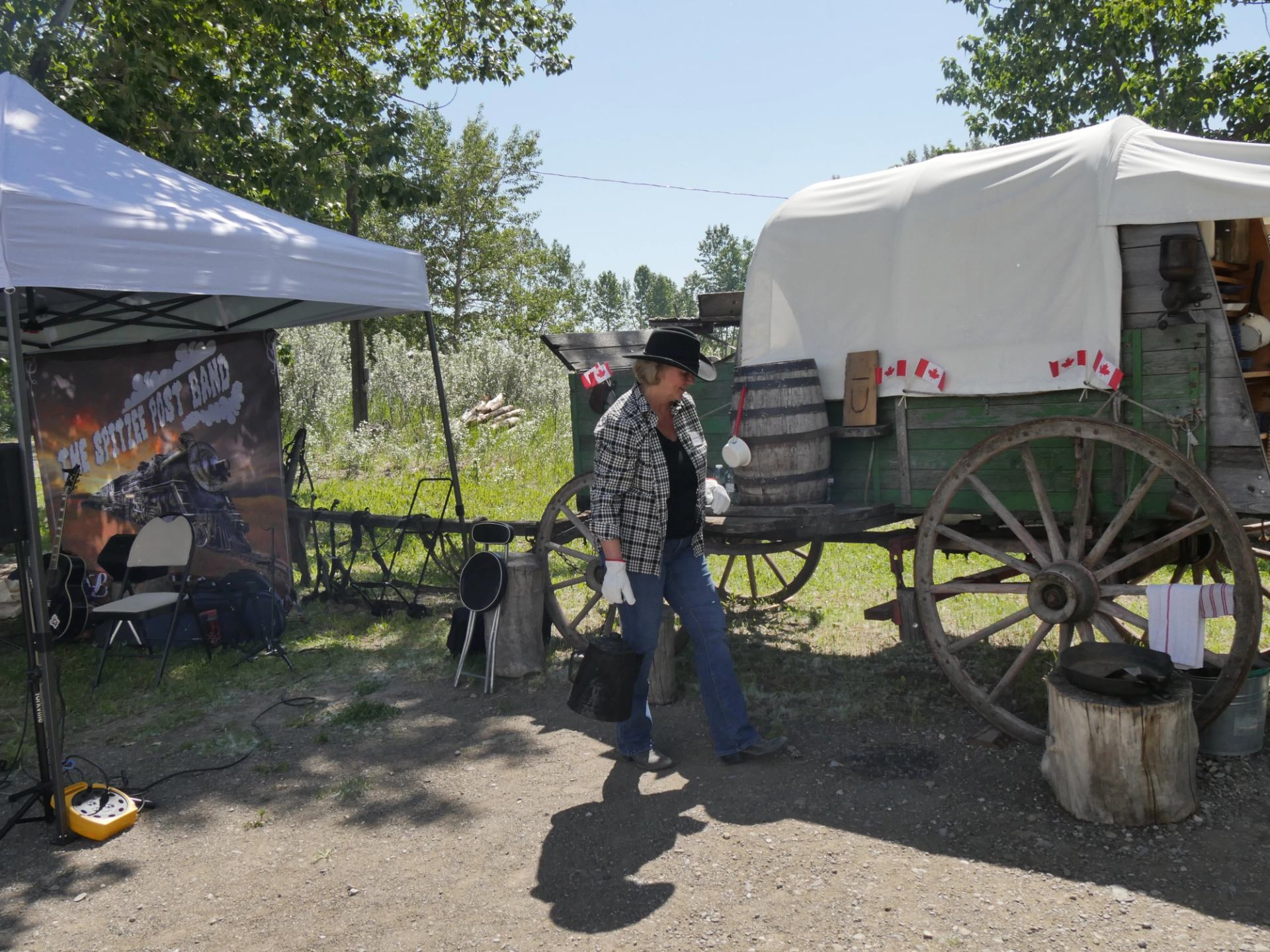 A historic wagon display with Canada flags and tents set up outdoors at Bar U Ranch.