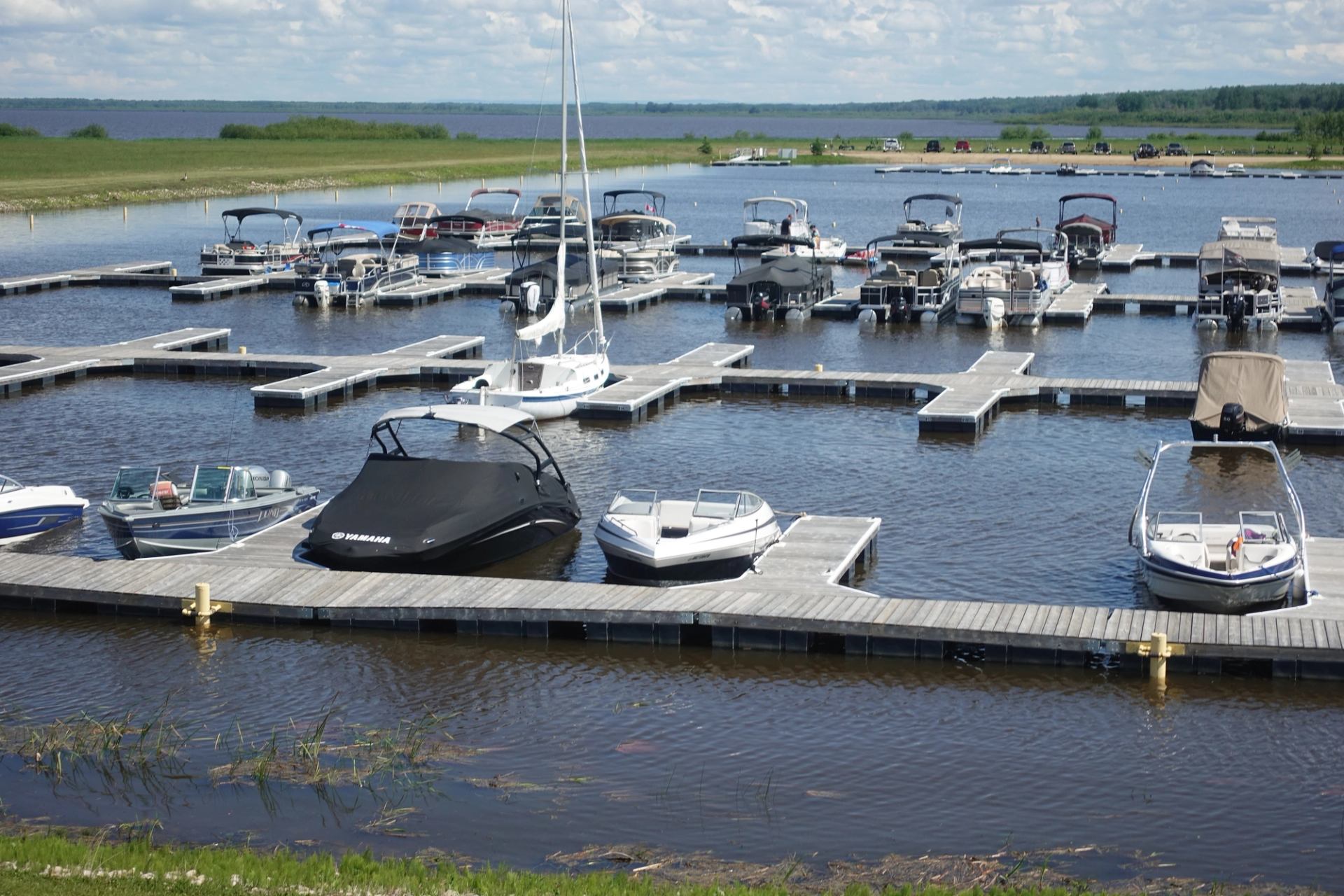 A group of motorized boats are tethered to a wooden dock.