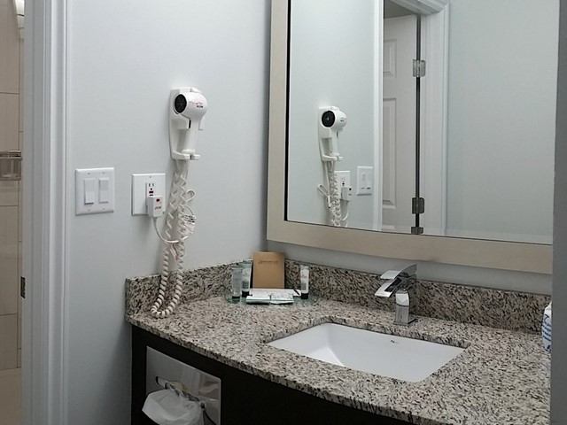 Motel bathroom vanity with sink, mirror, granite counter, and wall‑mounted hair dryer at El Lobo Motel.