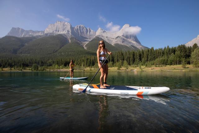 Friends stand up paddleboarding on Quarry Lake in Kananaskis Country.