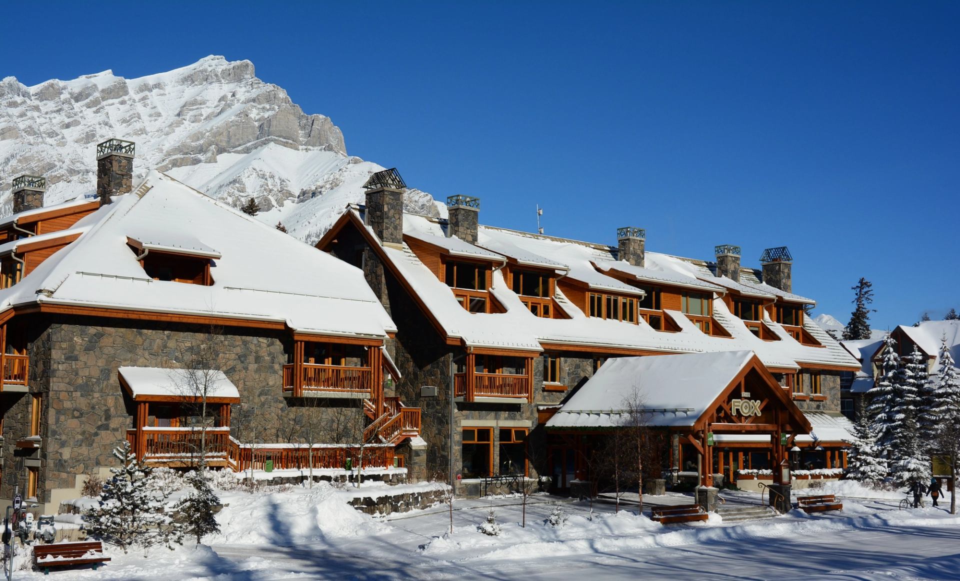 Snow-covered Fox Hotel with stone walls and mountain backdrop.