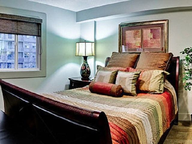 Cozy bedroom with colorful bedding and framed art in Corporate Suites of Calgary.
