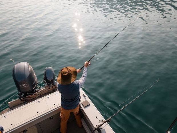 Person fishing off the boat of a Lake Minnewanka Cruise.