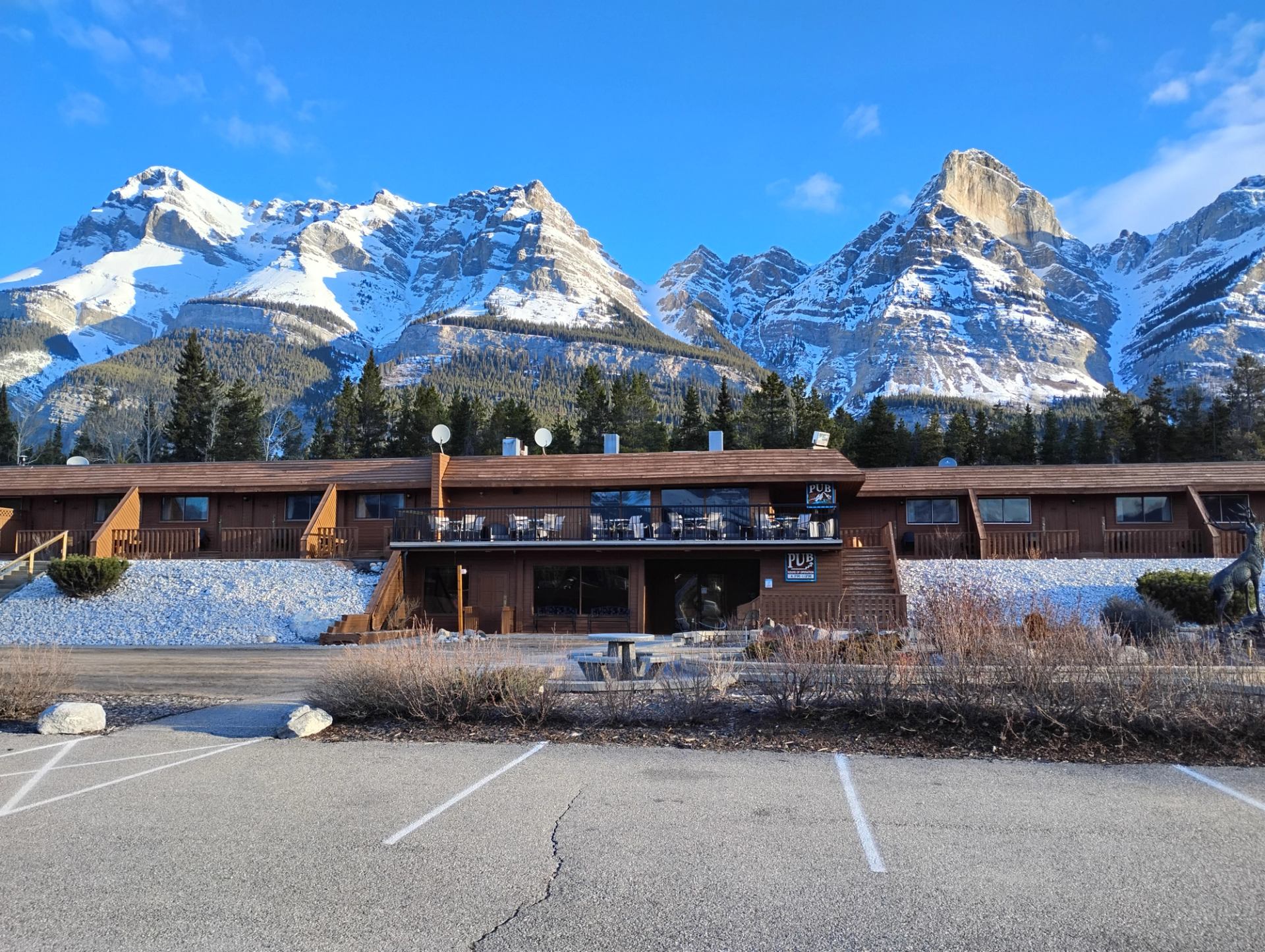 Wooden lodge at The Crossing Resort with towering snow-covered mountains behind it.