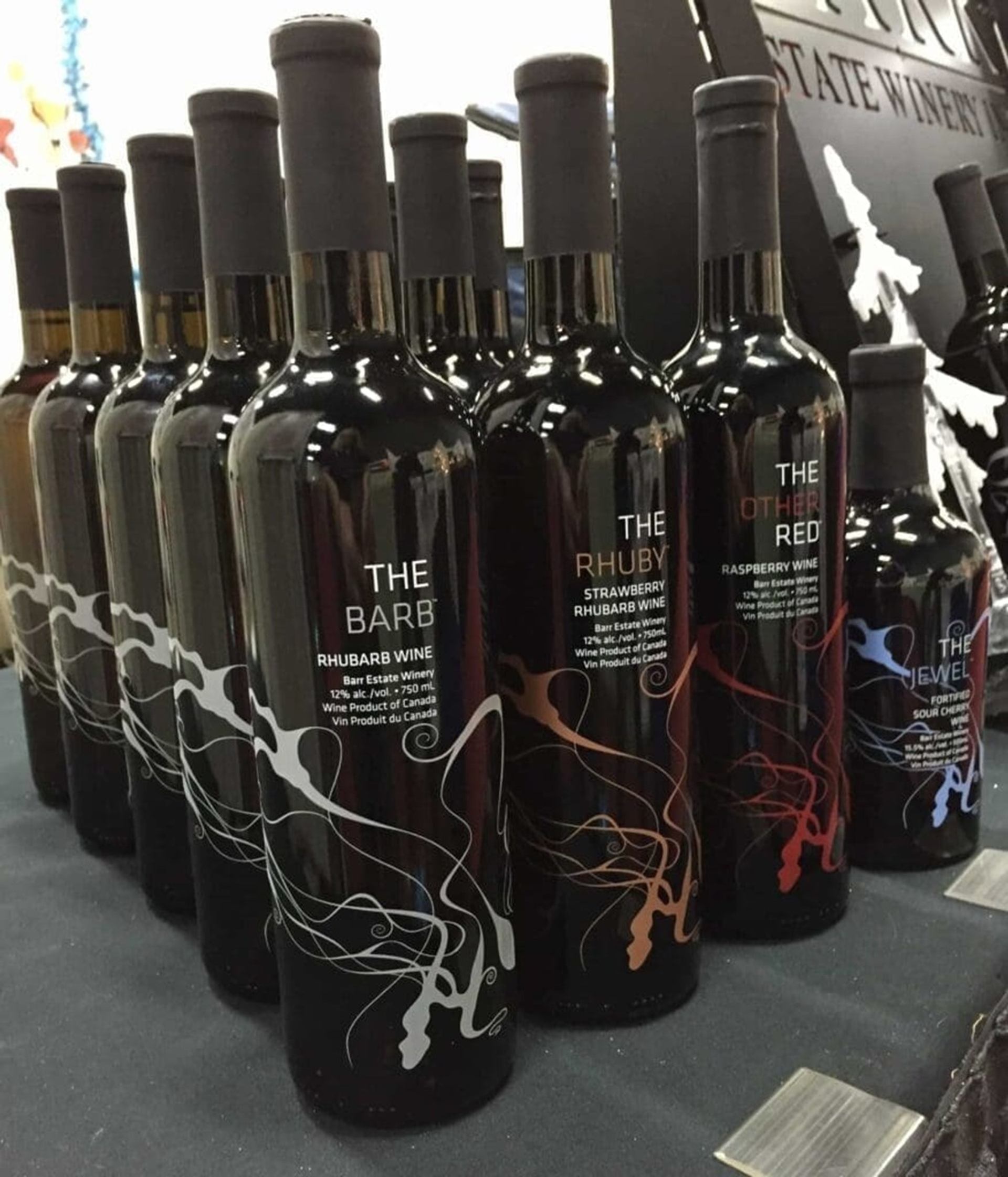 Wine bottles labelled The Barb, The Rhuby and The Other Red arranged on display.