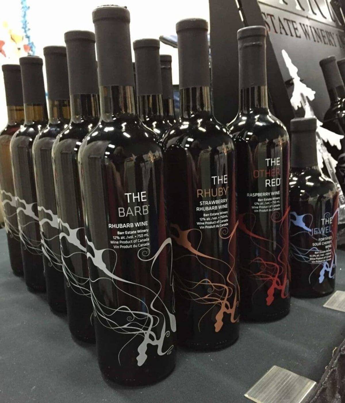 Wine bottles labelled The Barb, The Rhuby and The Other Red arranged on display.