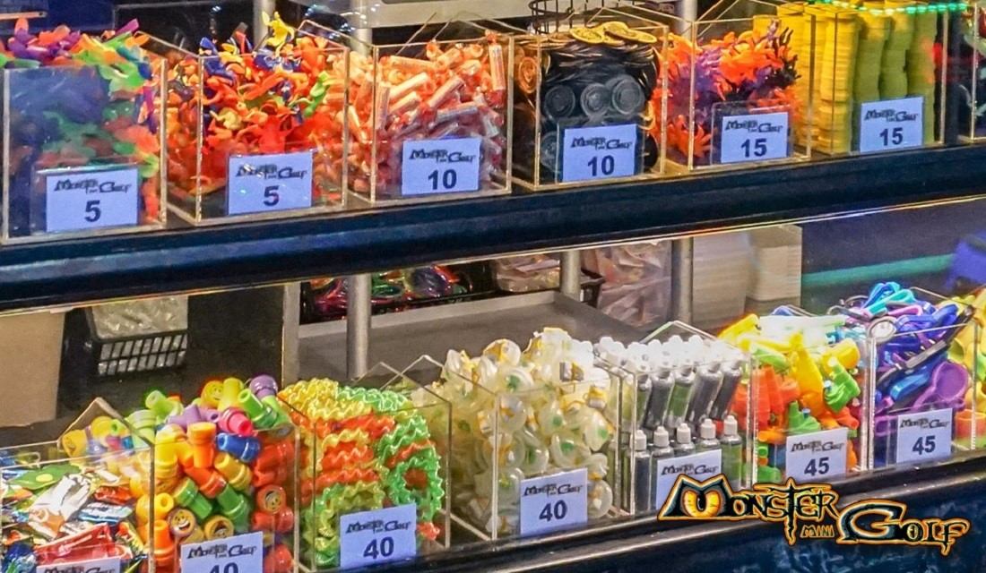 Prize bins with colourful toys and price tags beside Monster Mini Golf logo.