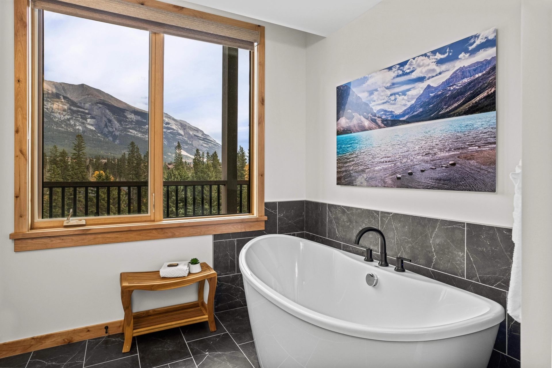 Freestanding bathtub beside a large window overlooking forested mountains.