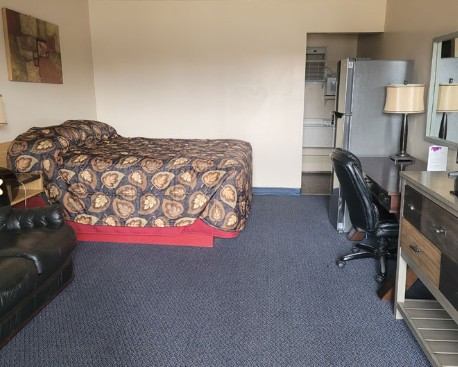 Guest room with queen bed, sofa, desk, and refrigerator.