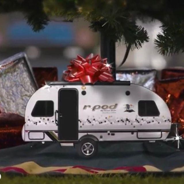 Mini R-Pod trailer with red bow under Christmas tree surrounded by wrapped gifts.