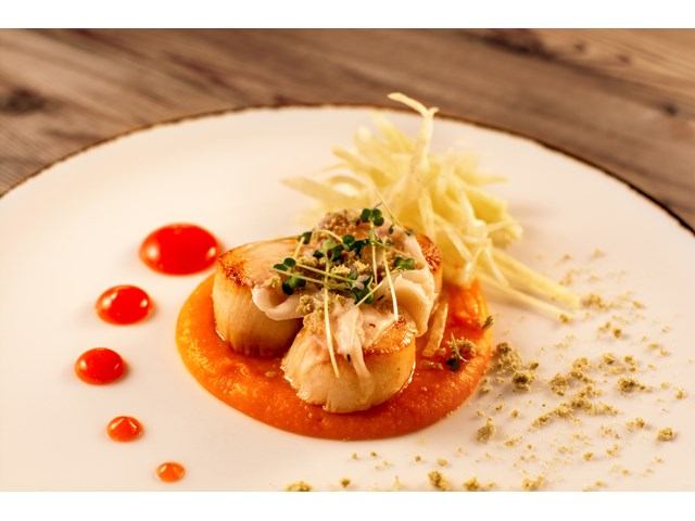 Seared scallops on orange puree with sprouts, shredded vegetables and red sauce dots.