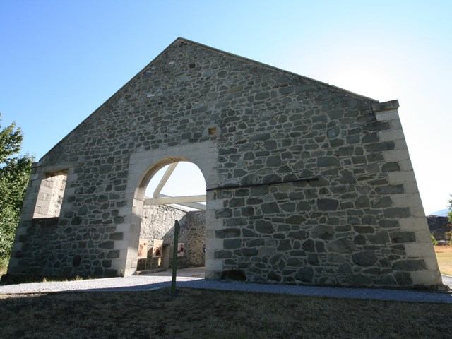 Stone ruins with large central arch at Leitch Collieries, sunlight casting shadows on historic stone walls.