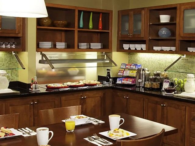 Hotel breakfast area with coffee station, cereals, and plated meals on a table.