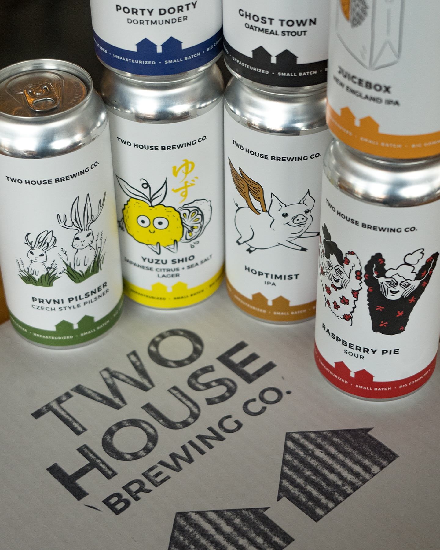Assortment of Two House Brewing cans arranged on a branded surface