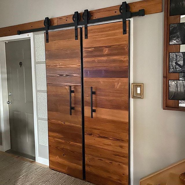 Wood sliding barn doors on black metal track inside a hallway.
