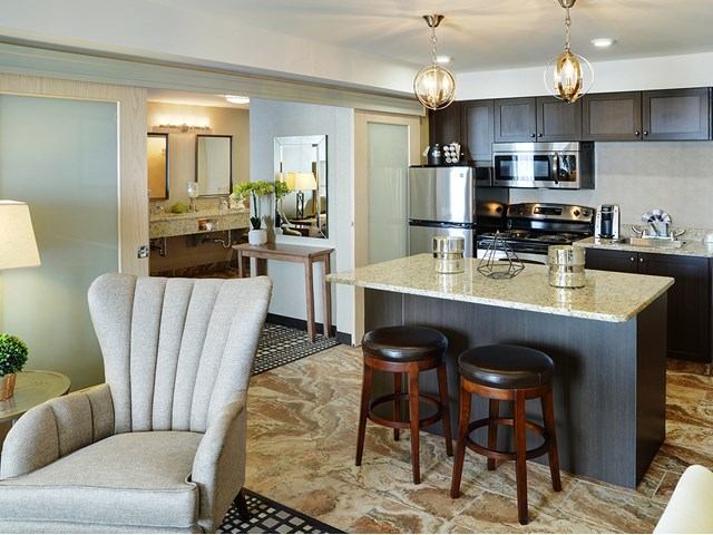 Elegant suite with full kitchen, island seating, and a plush armchair in view