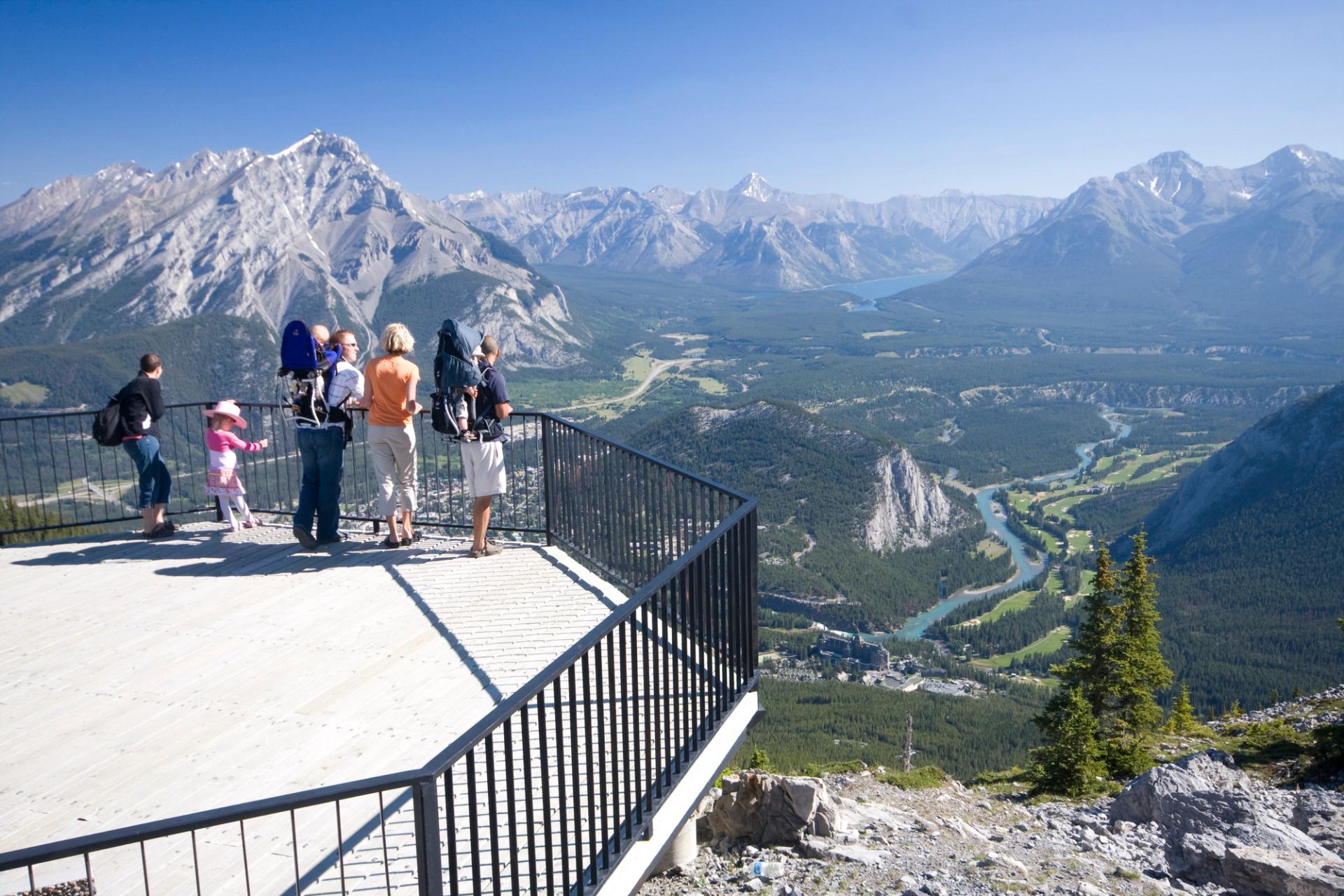 People standing on a summit lookout with wide mountain and valley views.