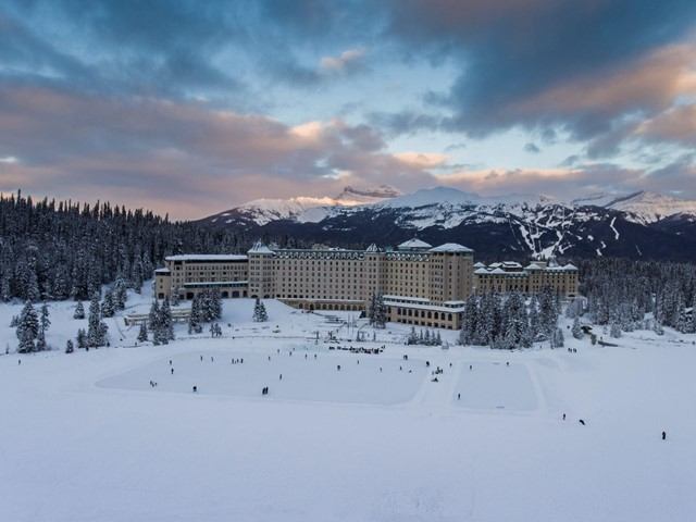 Luxury ski resort hotel surrounded by snow-covered trees and mountains.