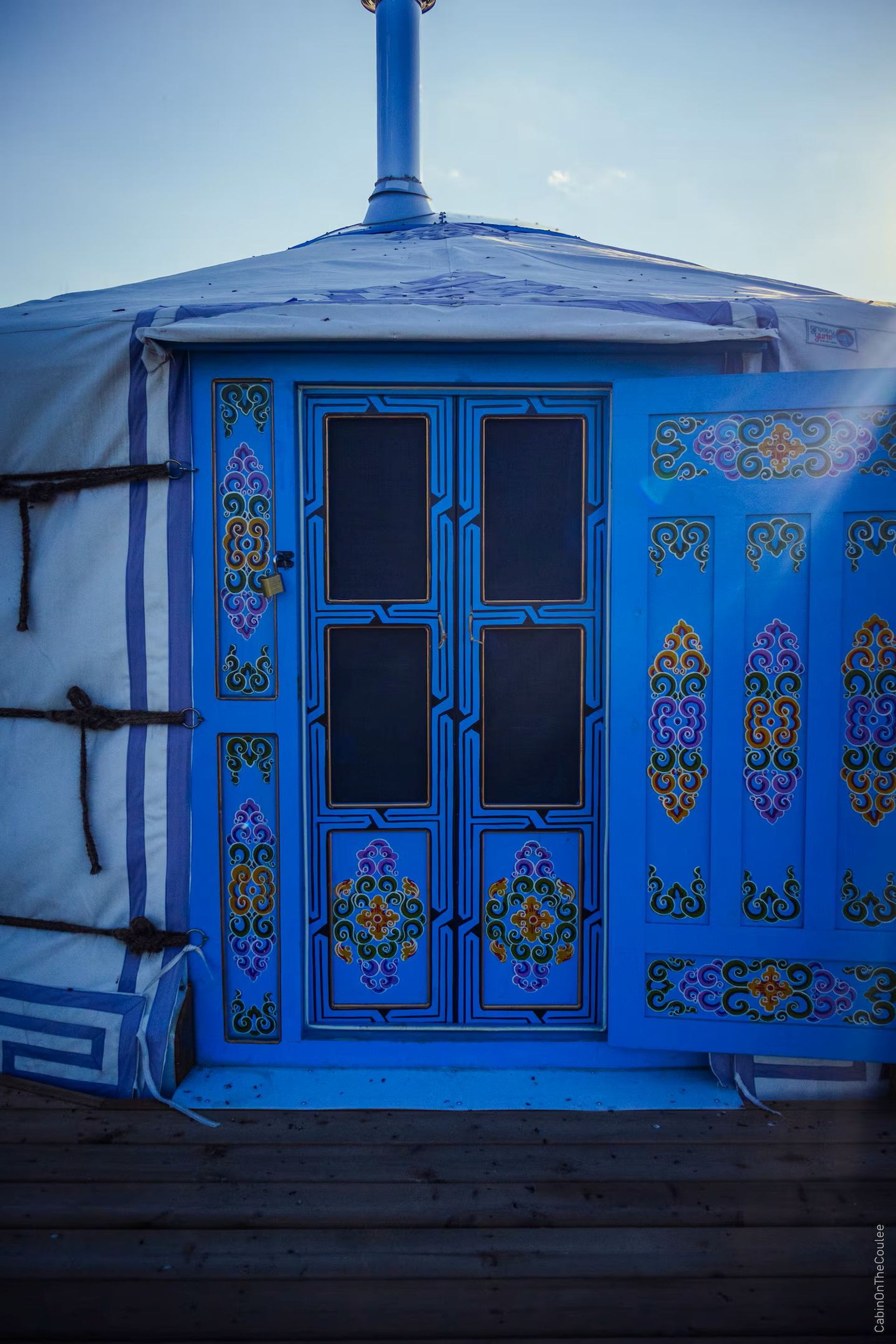 Close view of a blue yurt door decorated with colorful traditional patterns.