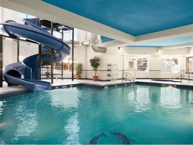 Indoor hotel pool area with blue waterslide and bright natural light.