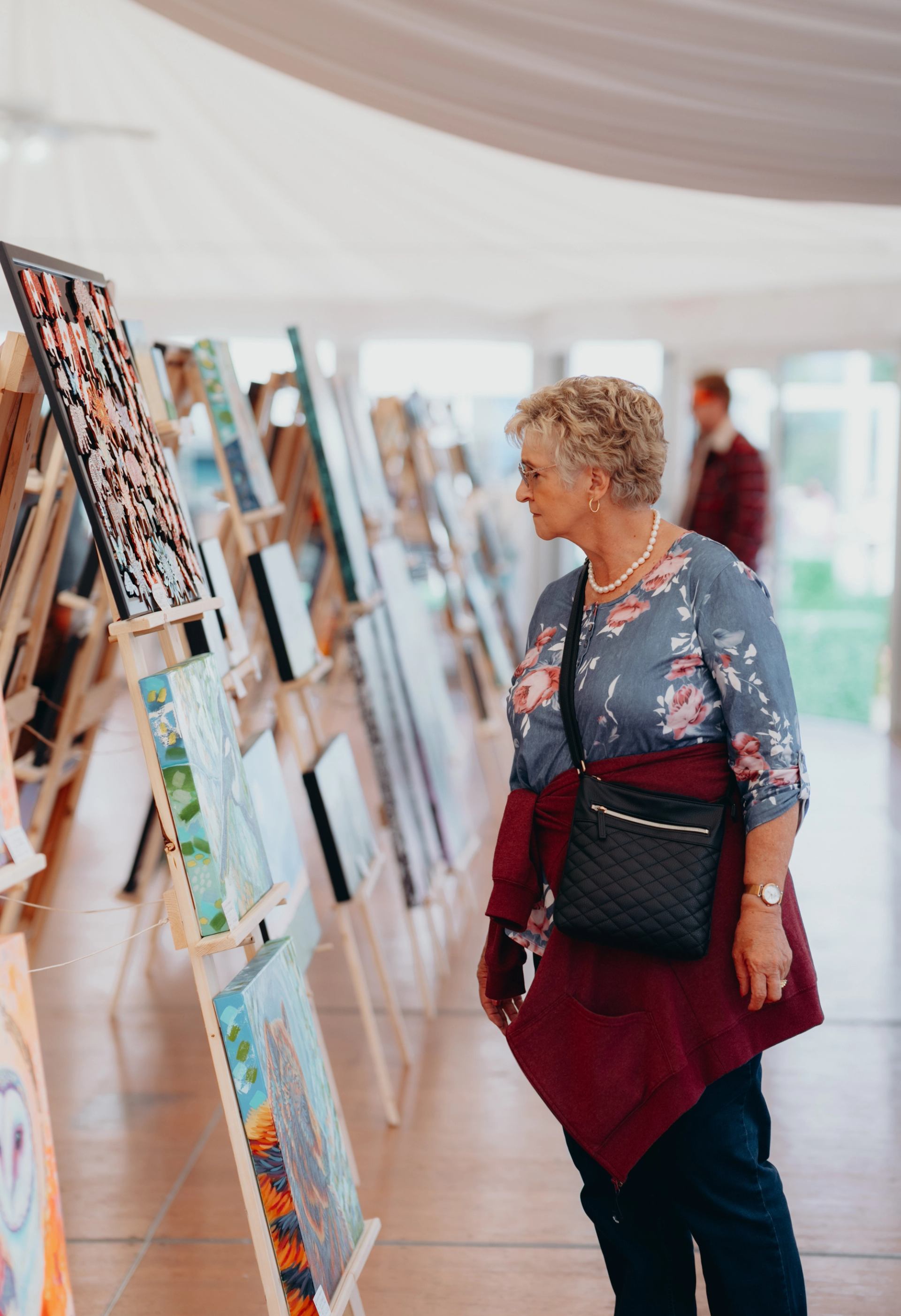 A guest browses framed paintings displayed on easels.