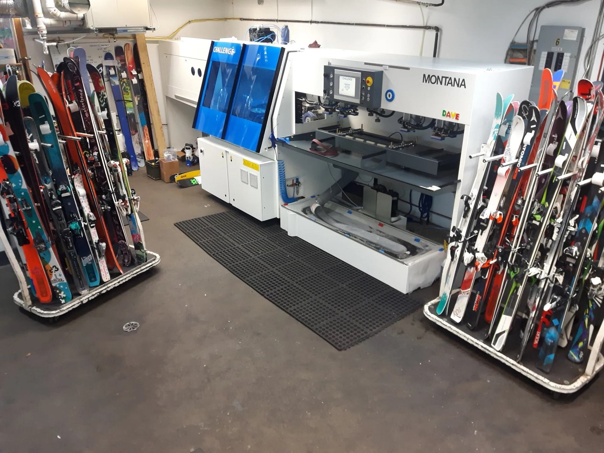 Ski tuning workshop with racks of skis and a Montana service machine.