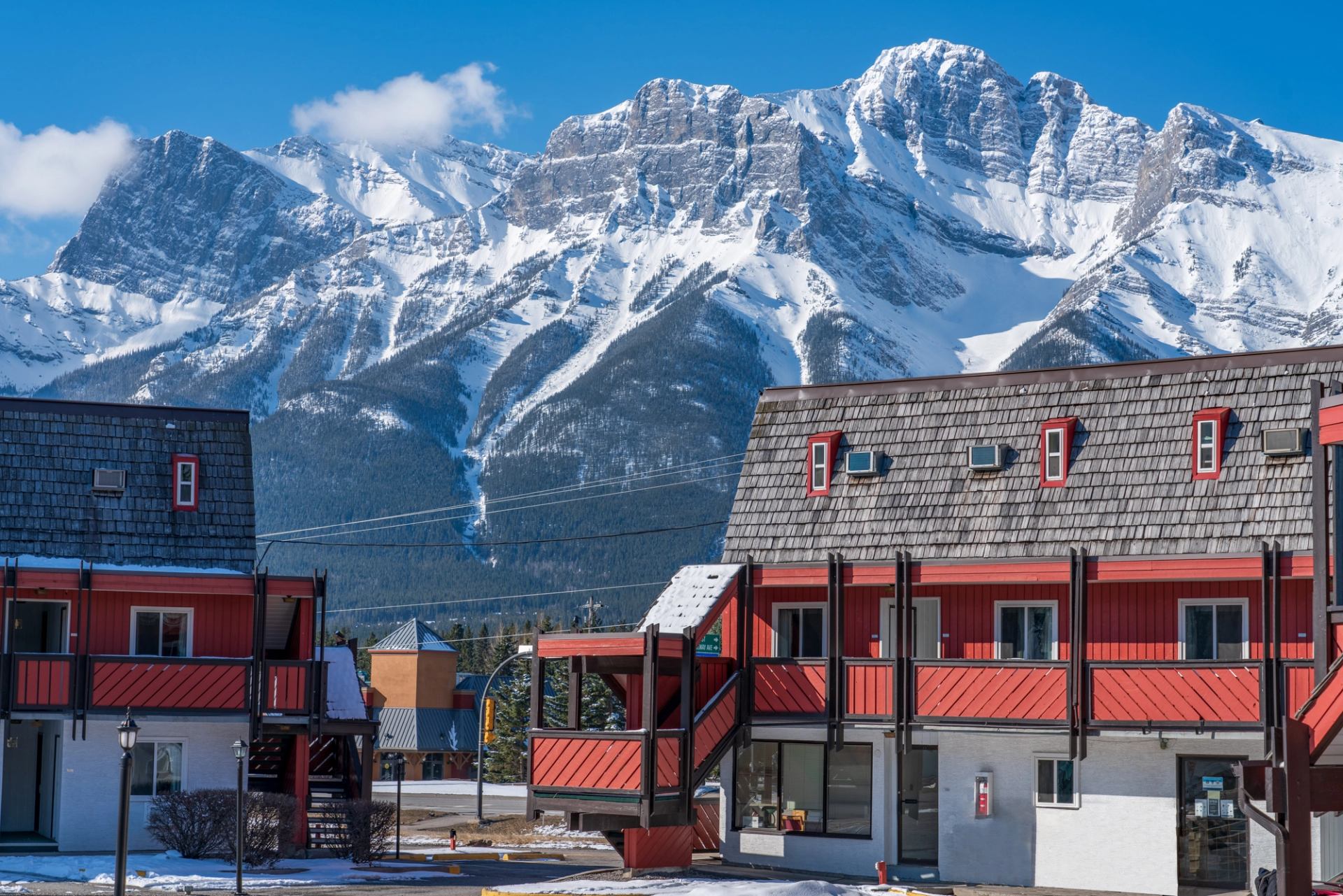 Lodge buildings with snowy mountains and blue sky in the background.