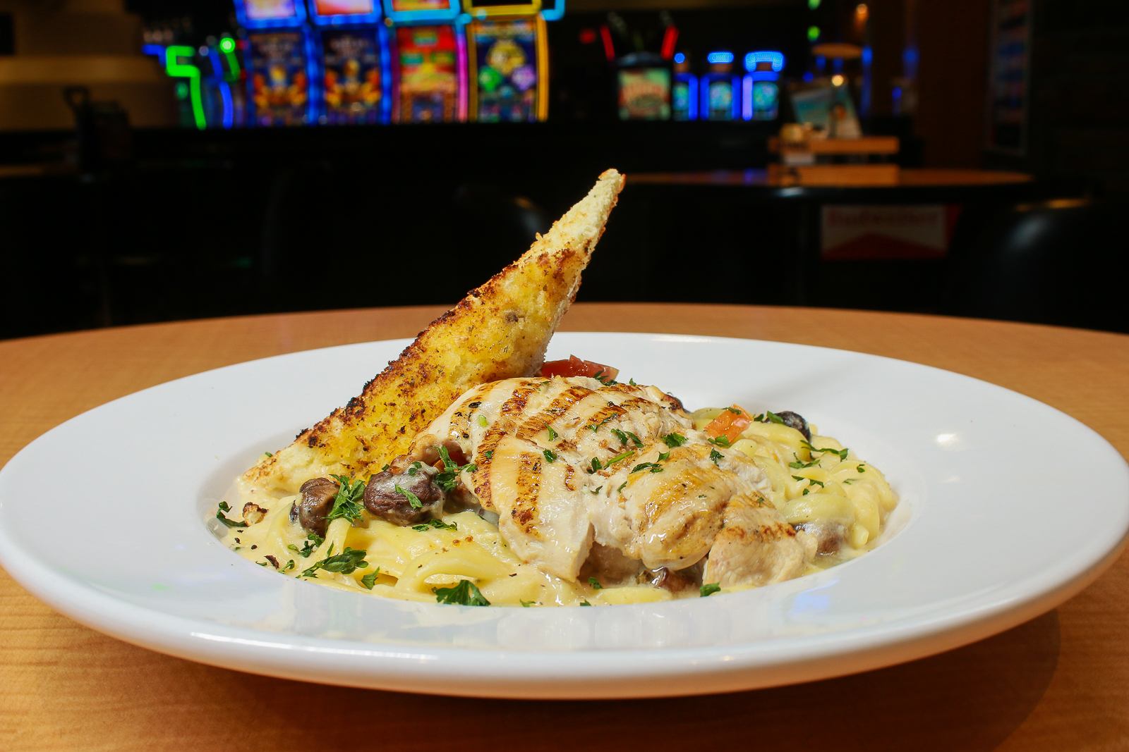 Grilled chicken dish with sauce and bread in a casino lounge setting.