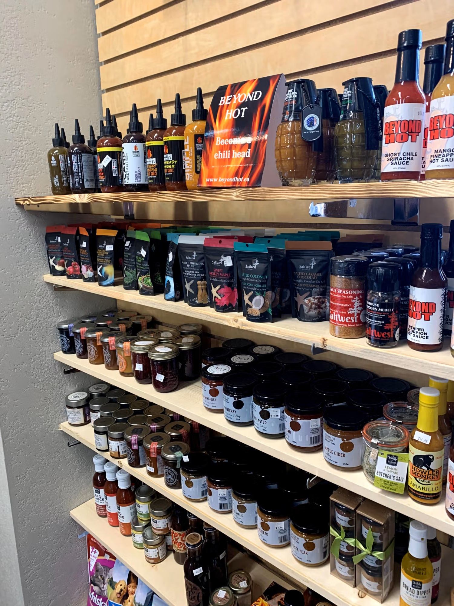 Grocery store shelves displaying hot sauces, spice mixes, jars of preserves and condiments.