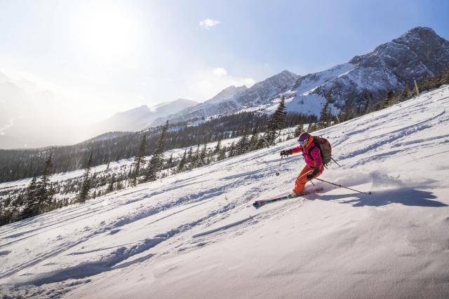 A skier with a backpack, carving and skiing at Fortress Mountain in Kananaskis Country