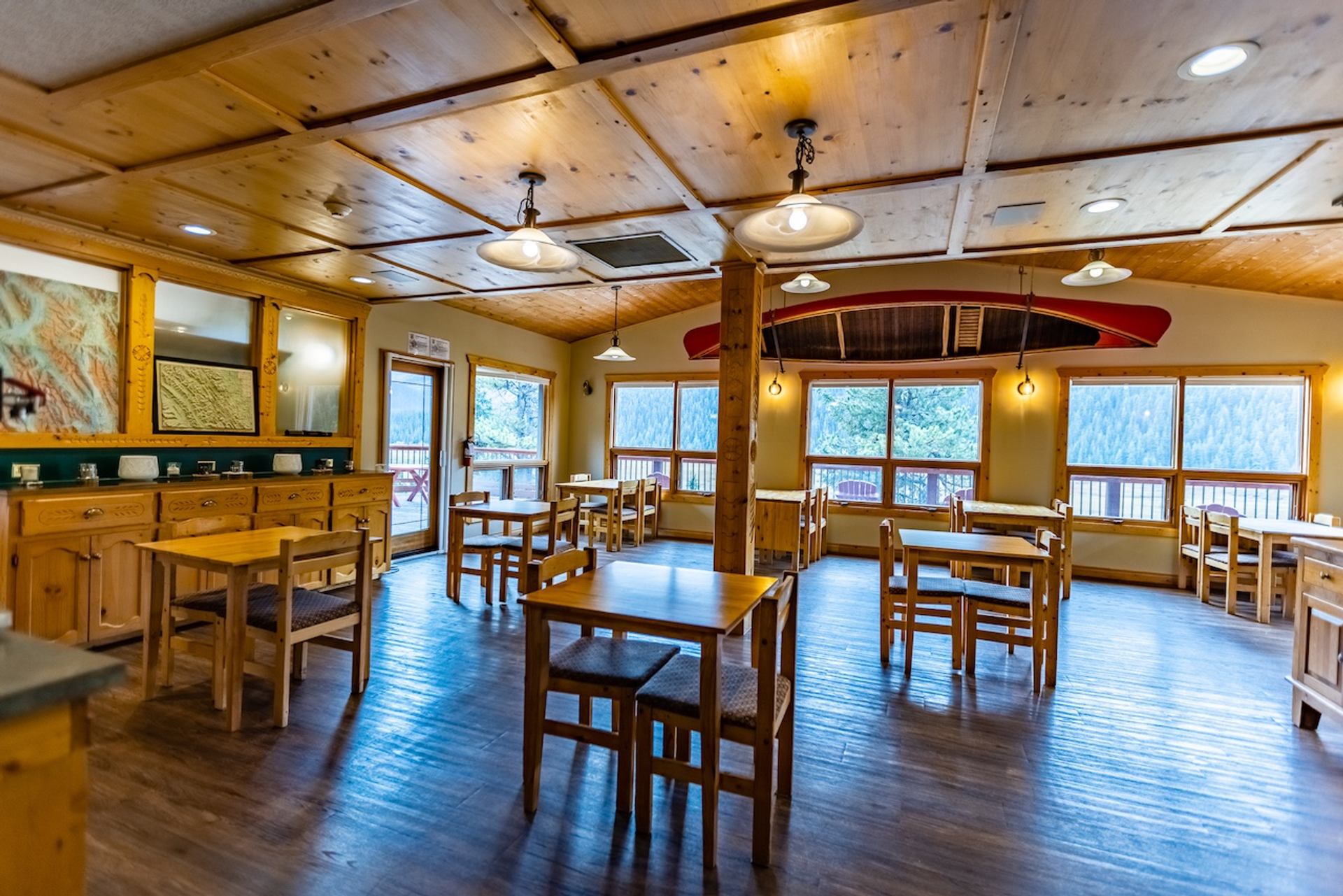 Bright dining room with wooden tables, large windows, and forest views