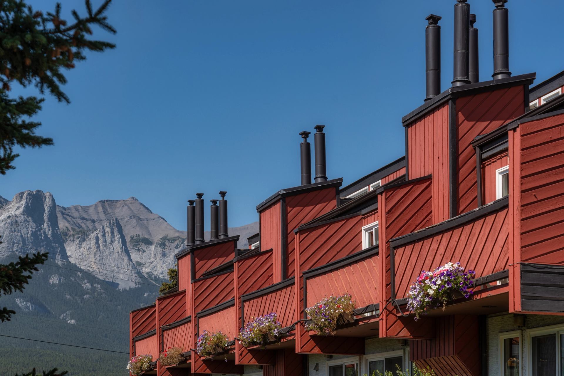 Red balconies with mountain views and flower pots.